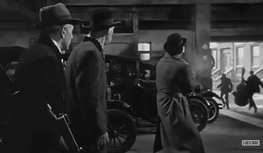 Three men in a garage watch two men run away carrying musical instruments.