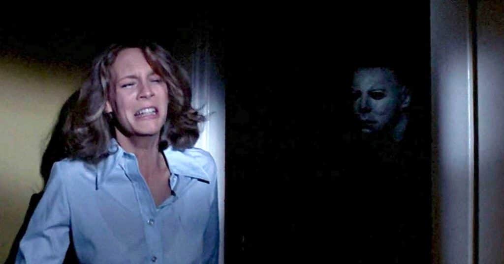 jamie lee curtis as Laurie strode hiding from Michael Myers as he emerges from the shadows