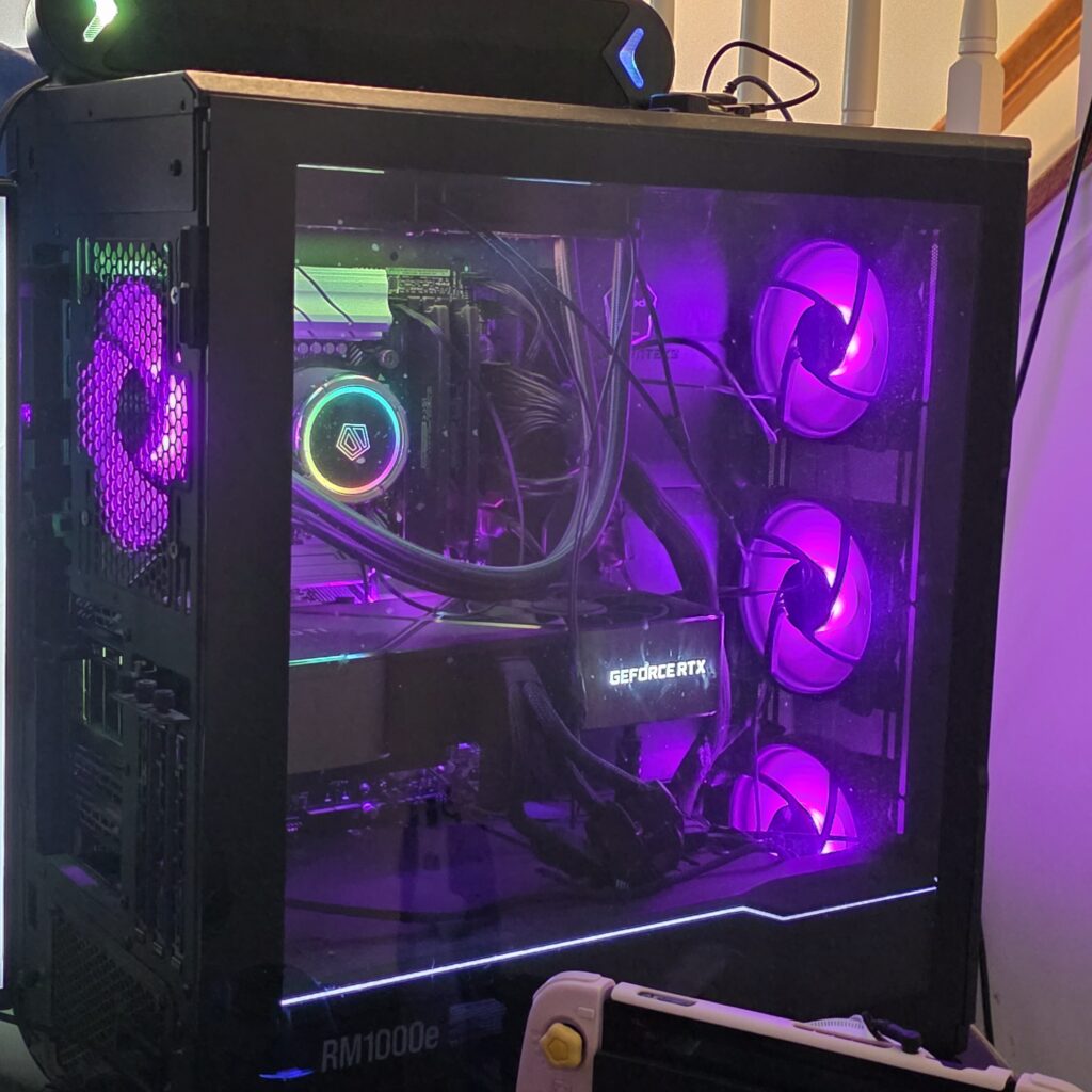 An RGB custom-built PC with purple fan lights in a black case.