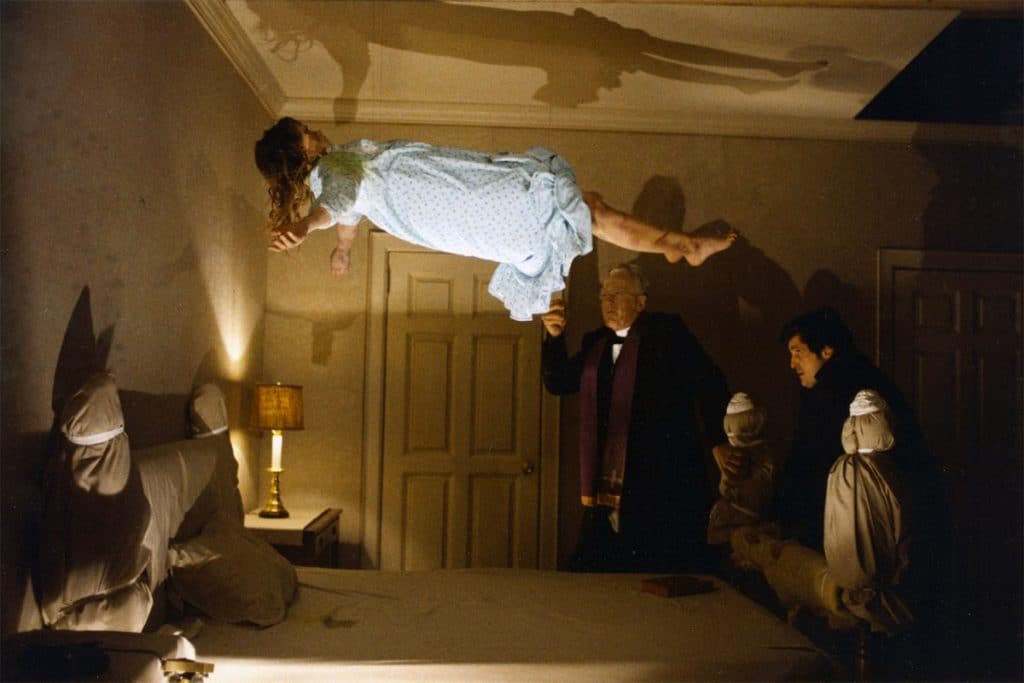 linda blair as regan levitating above bed as people watch