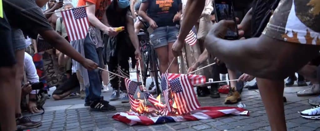 USA flags being set on fire by angry protestors.