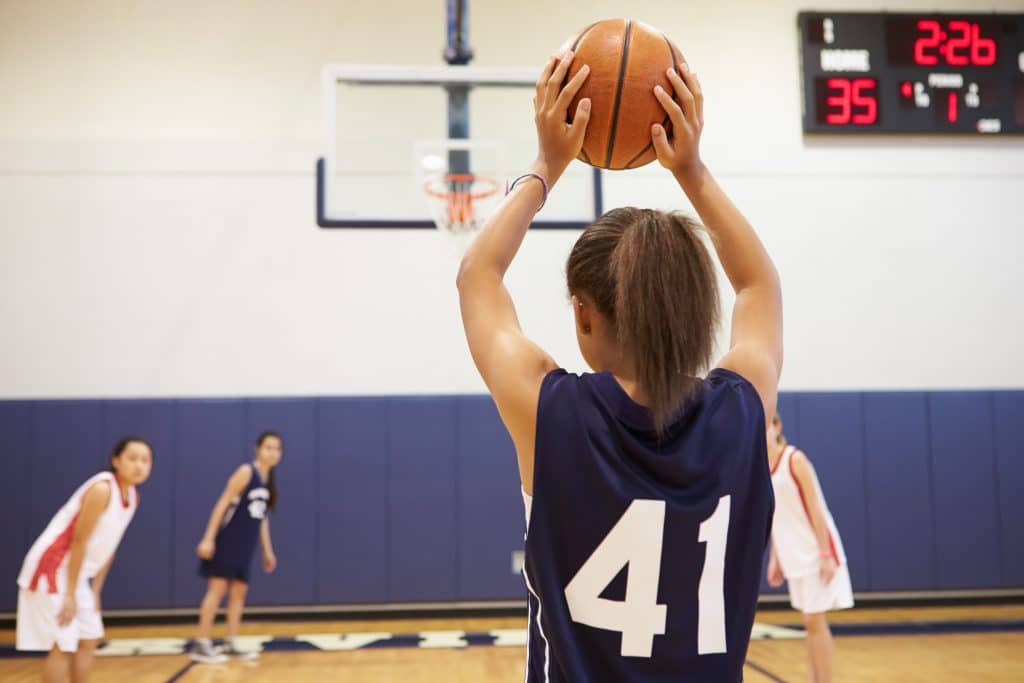 The players on the basketball court are all focused on the game; no one is constantly watching the scoreboard.