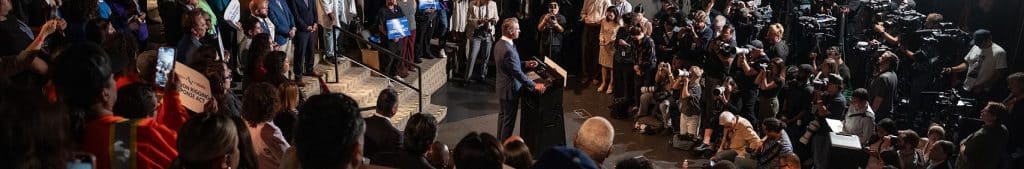Gavin Newsom's YouTube Channel Banner depicts a horizontally stretched image of Newsom in the center surrounded by much media members such as journalist, photojournalist and gathers, taken from a dynamic left field shot.