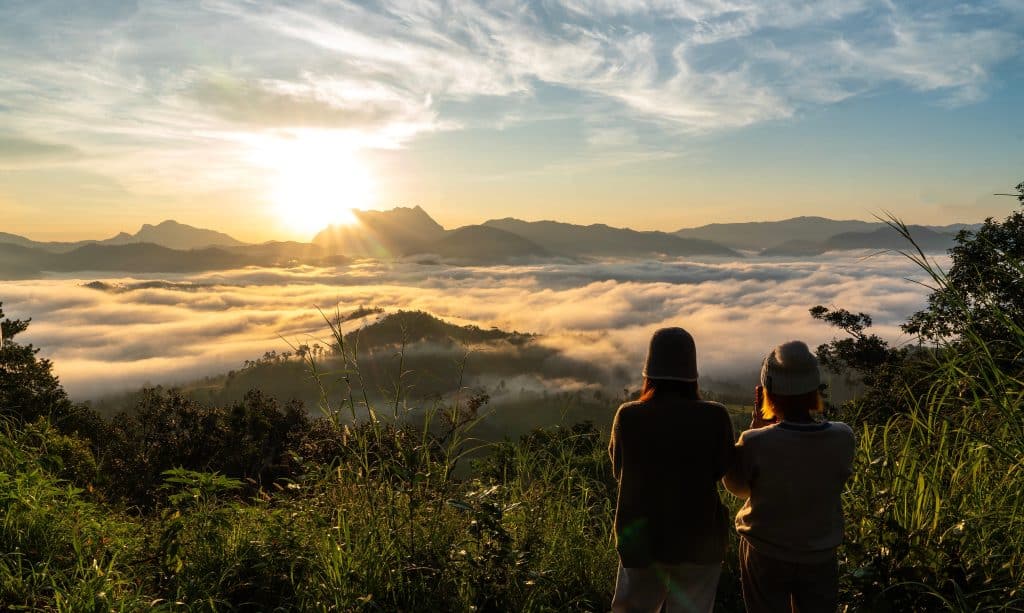 Trill Mag Mountain View Two people admiring the natural beauty of the sun hovering over a mountain.