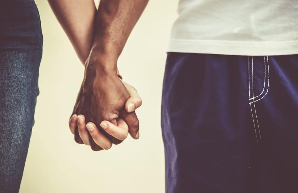 An interracial gay couple holding hands