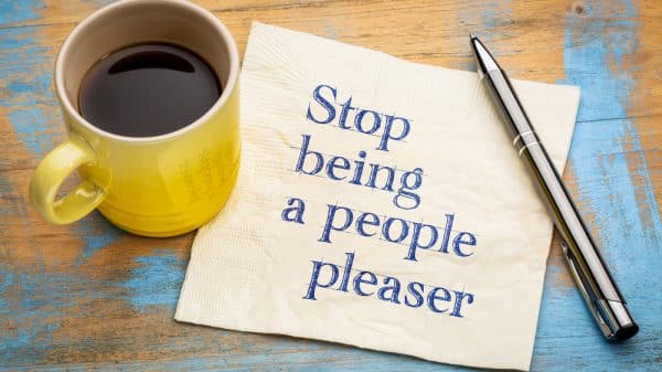 Stop being a people pleaser note next to coffee