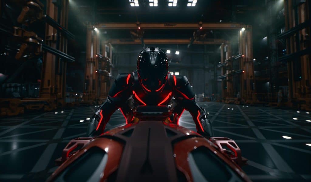 Ares, a man in black armor with red accents, on a giant black Light Cycle in a warehouse.