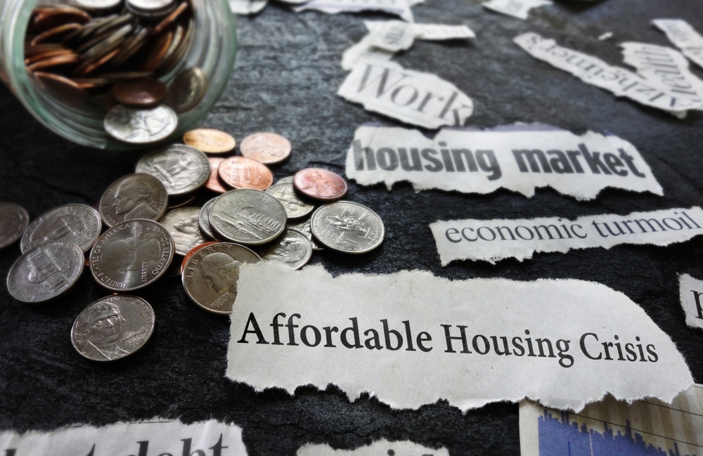Headlines about the affordable housing crisis scattered among loose change. (Image: Shutterstock)