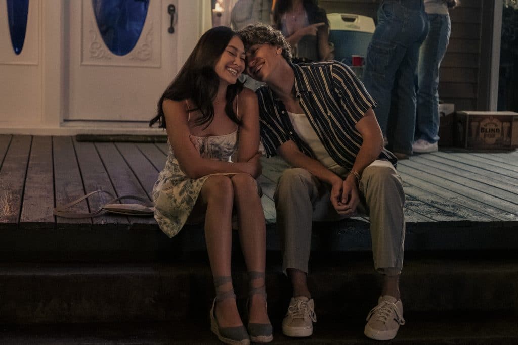 An image of Isabel "Belly" Conklin and Jeremiah Fisher cosied up sat on a deck.