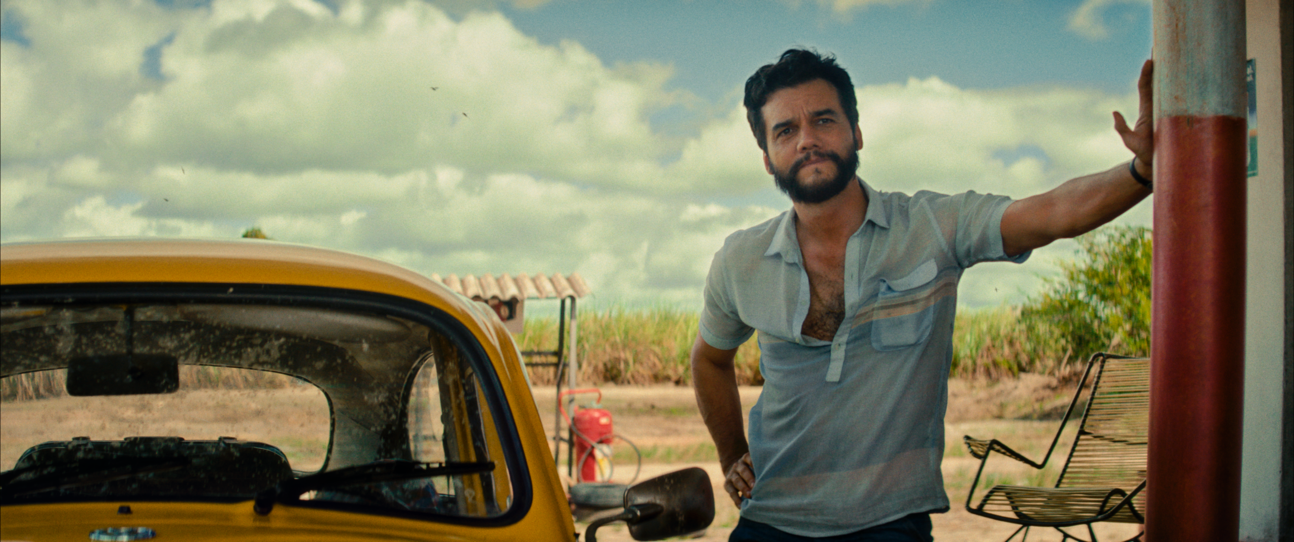 Marcelo (Wagner Moura) standing pensively at a gas stop.
