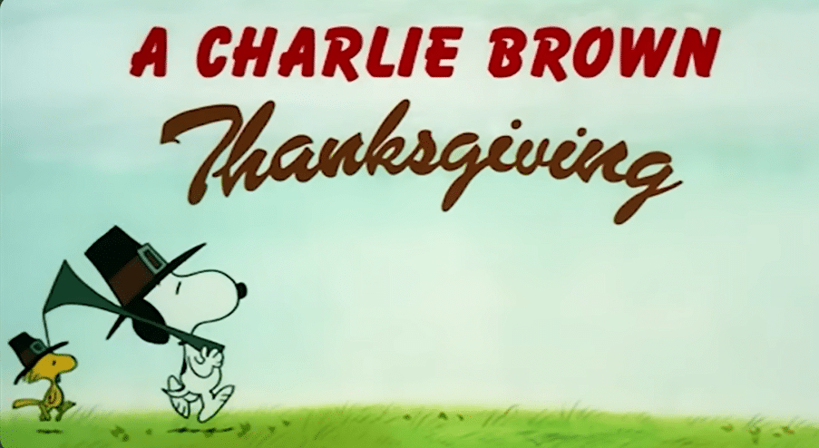 Snoopy walking by a sign that says 'A CHARLIE BROWN Thanksgiving'
