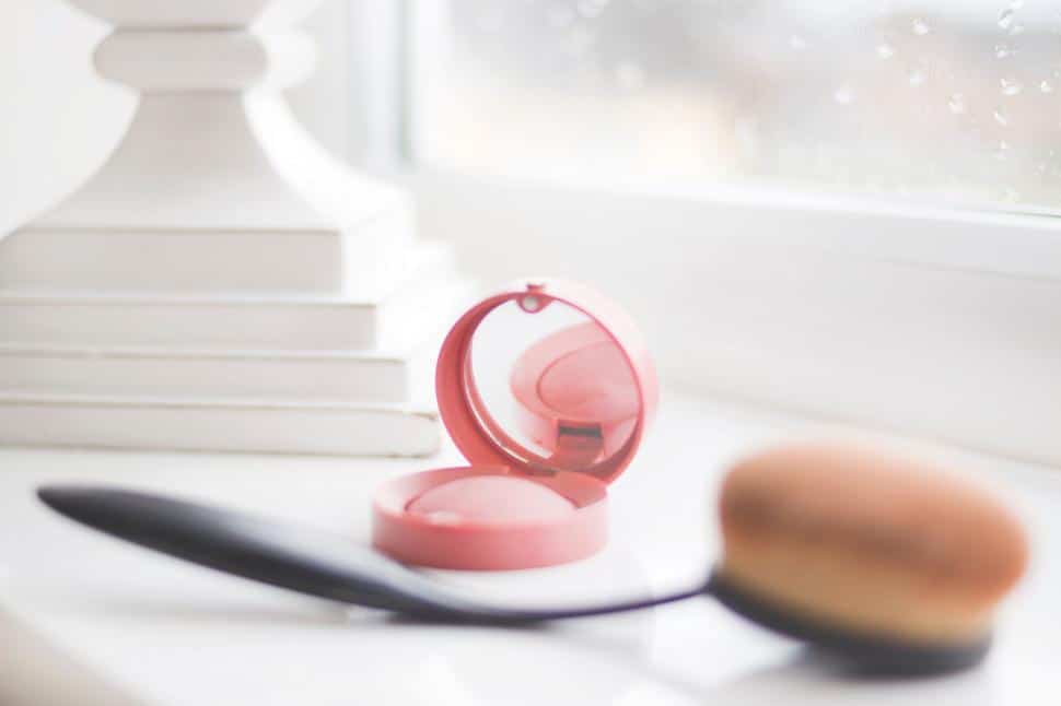 compact mirror case with makeup brush on table