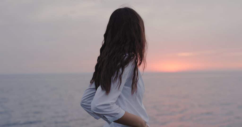 Young girl looking at the sea view and thinking at the overcast day