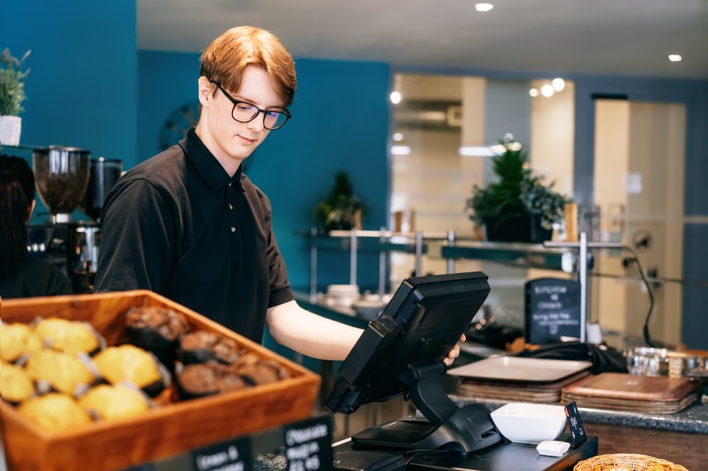 A young man behind the till at a cafe