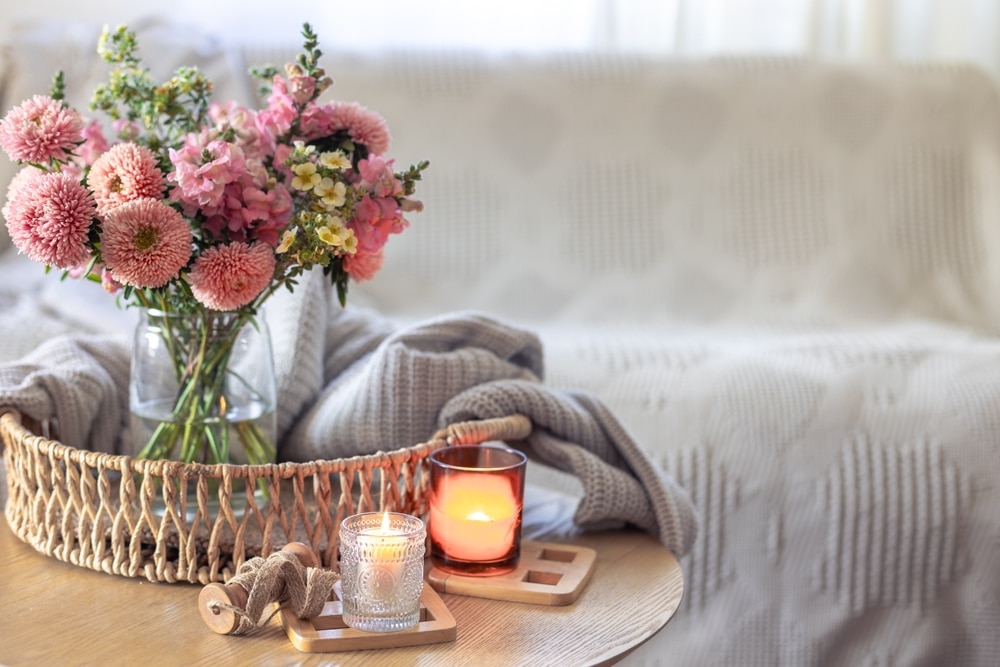 flowers in a vase on an end table with candles lit