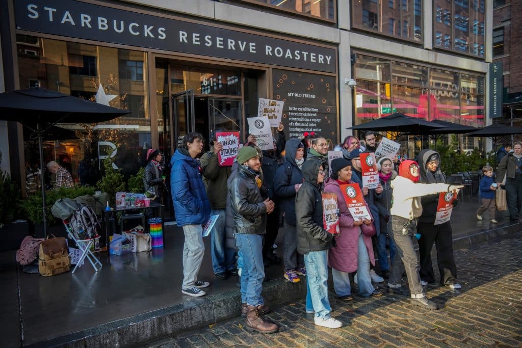 Starbucks workers stand outside the coffee chain with signs supporting the union, December 2024