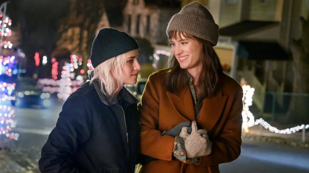Abby and Harper standing together in their coats and hats, surrounded by holiday lights.