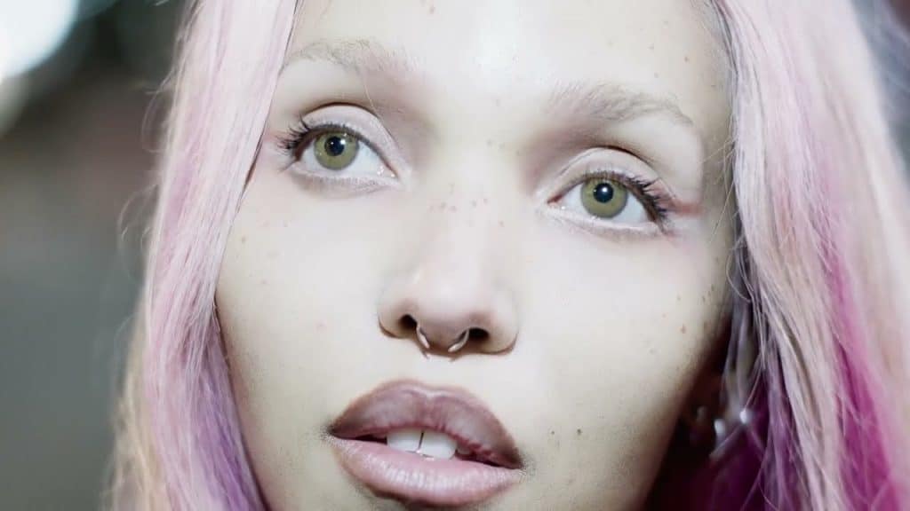 FKA twigs wears pink wig and looks into distance.