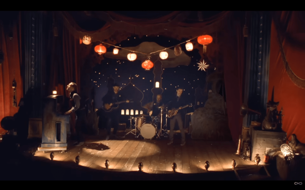 Coldplay performing on a small stage with a Christmas backdrop.