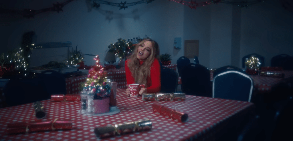Jade from Little Mix at a Christmas table, singing.