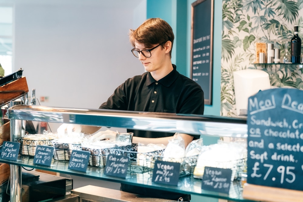 A young man working behind a cafe counter.