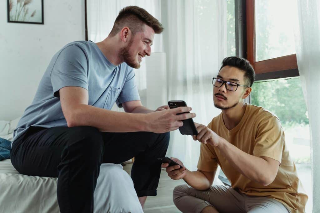 Two men smiling and looking at a smartphone.