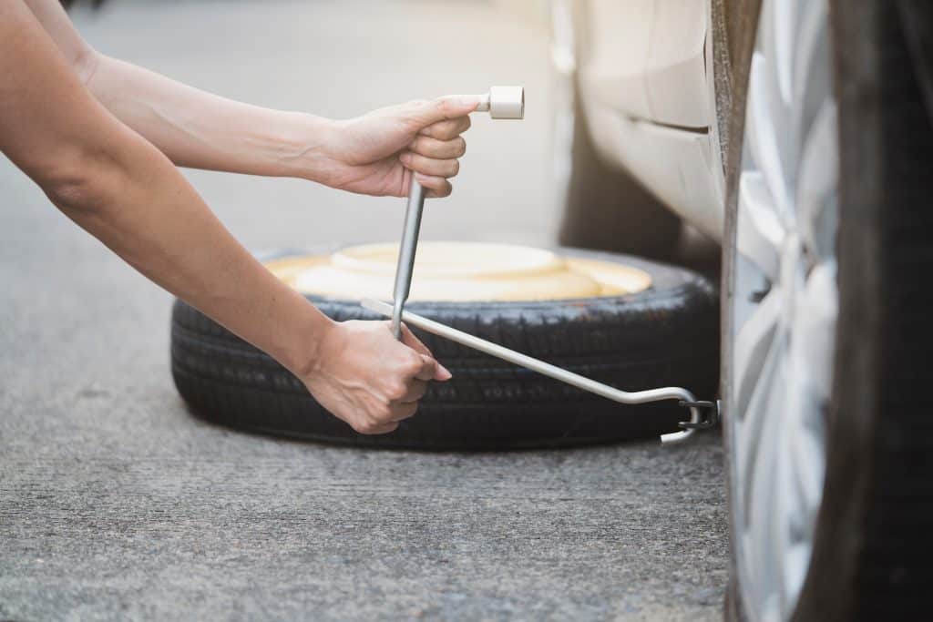 Person changing a tire on the side of the road
