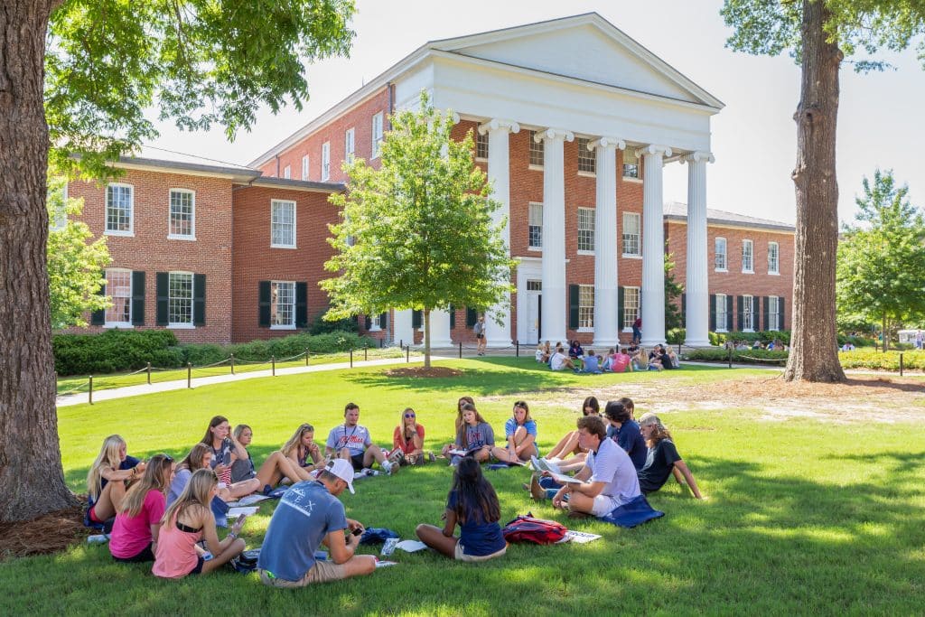 A group of students sitting outside on a college campus.