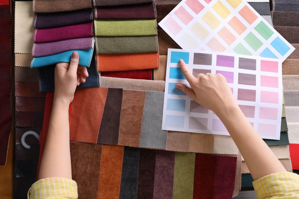 Woman choosing among colorful fabric samples, closeup.