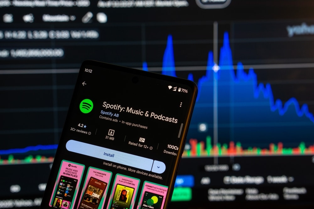 Phone with Spotify in front of screen that is showing a graph.