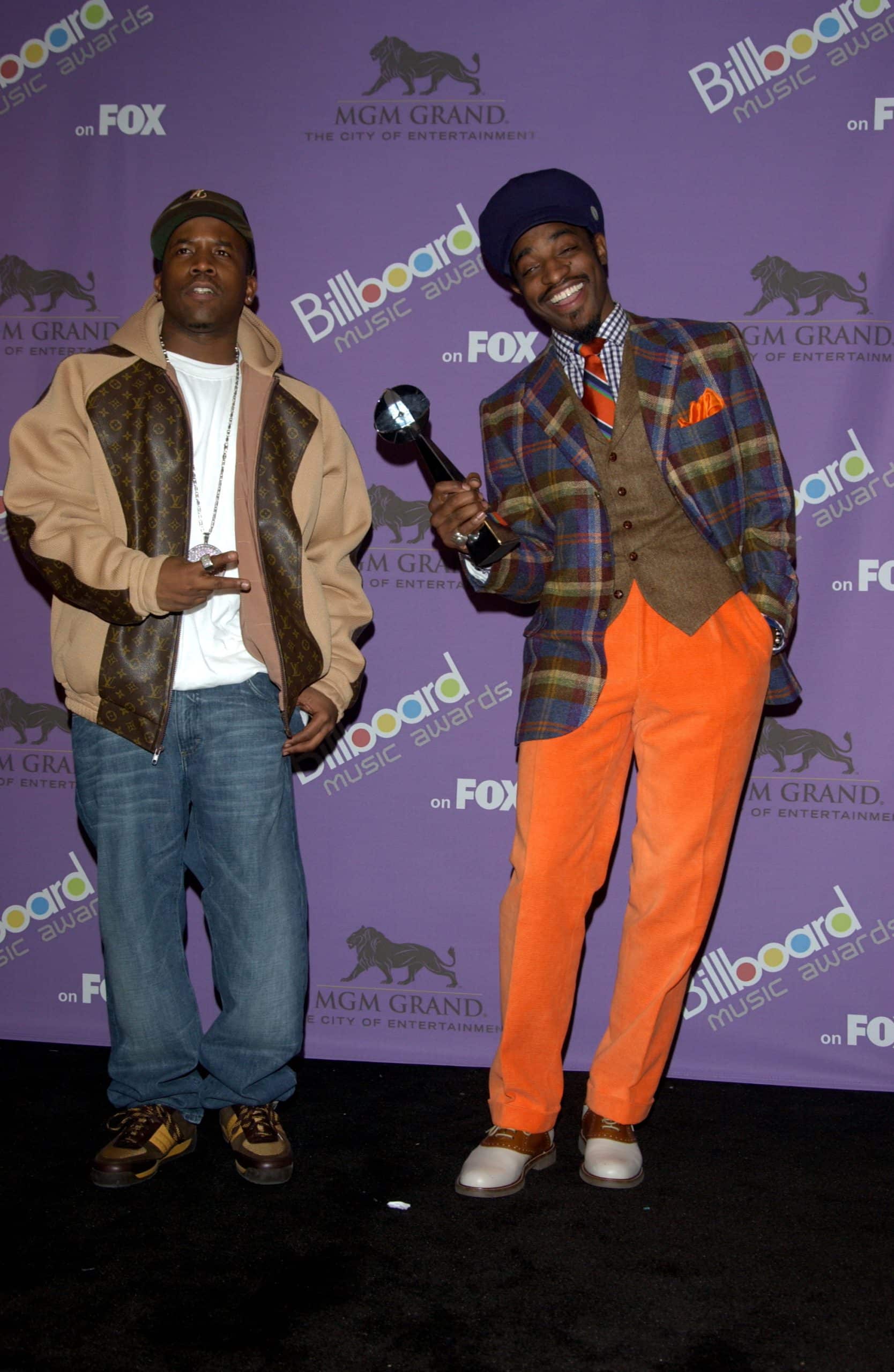 Andre 3000 standing on the right dressed in orange, blue, and brown and the Billboard Music Awards.