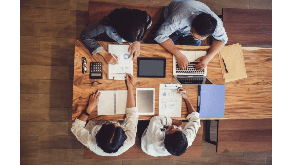 Four people sitting at a long table working on a project.