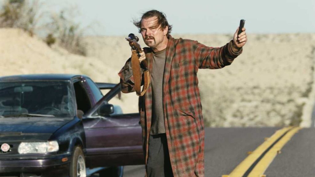 Leonardo DiCaprio stands next to a car.