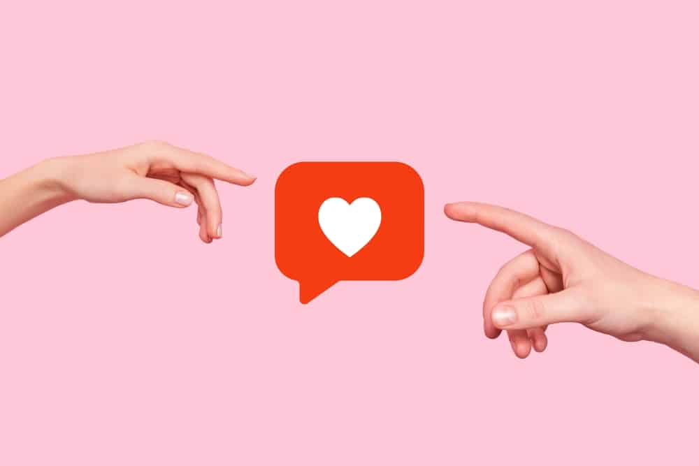 Two hands coming from the left and right reach for each other and a heart in the middle.