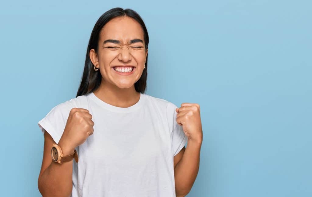 Young asian woman wearing casual white t shirt excited for success with arms raised and eyes closed celebrating victory smiling. winner concept.