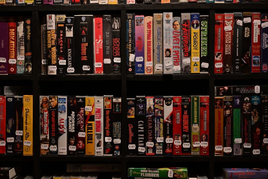 a collection of vhs tapes displayed on a bookshelf showcasing how touch and ownership are significant