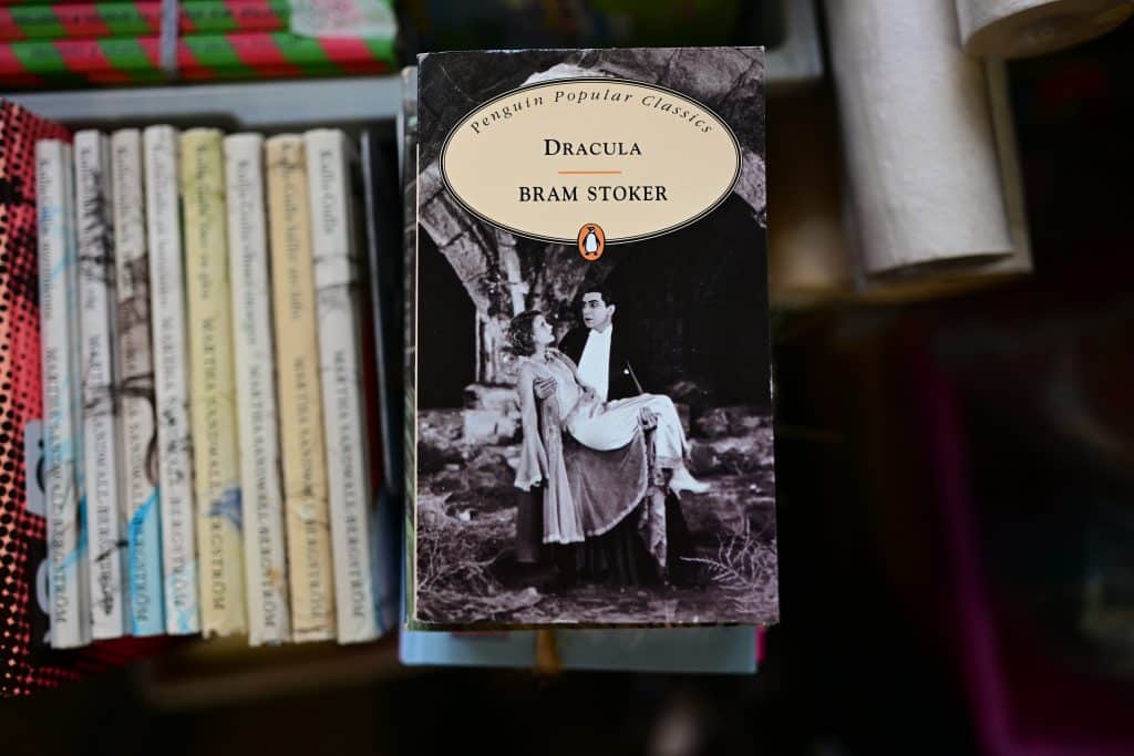 A cover of Bram Stoker's Dracula shows a vampire man holding a woman bridal style. It's black and white.