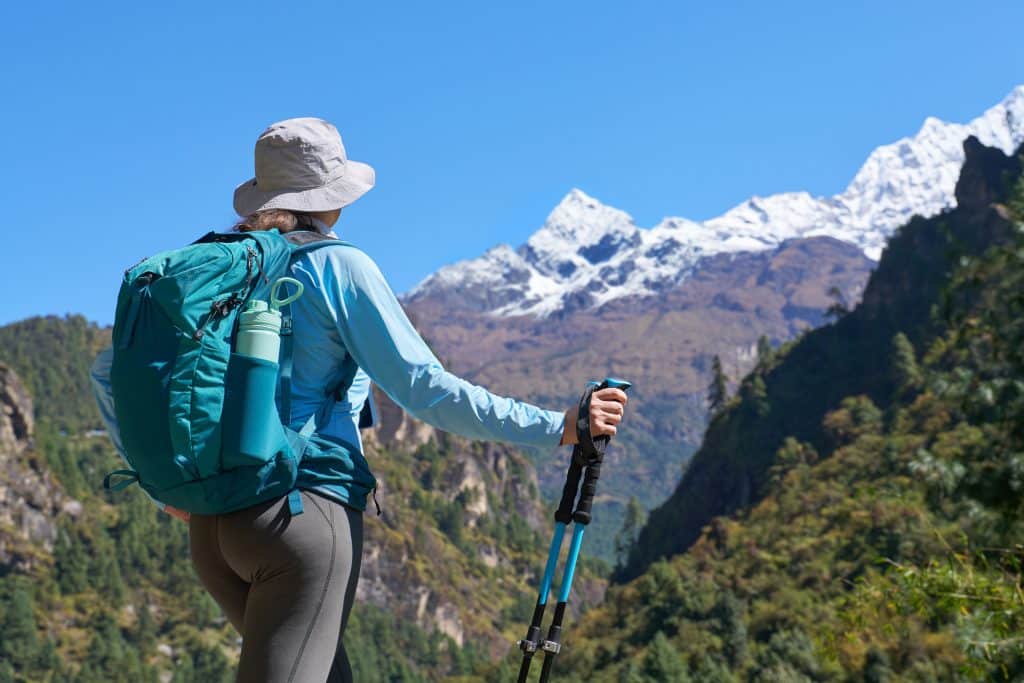 A lady hiking. In front of her are tall snowy mountains.