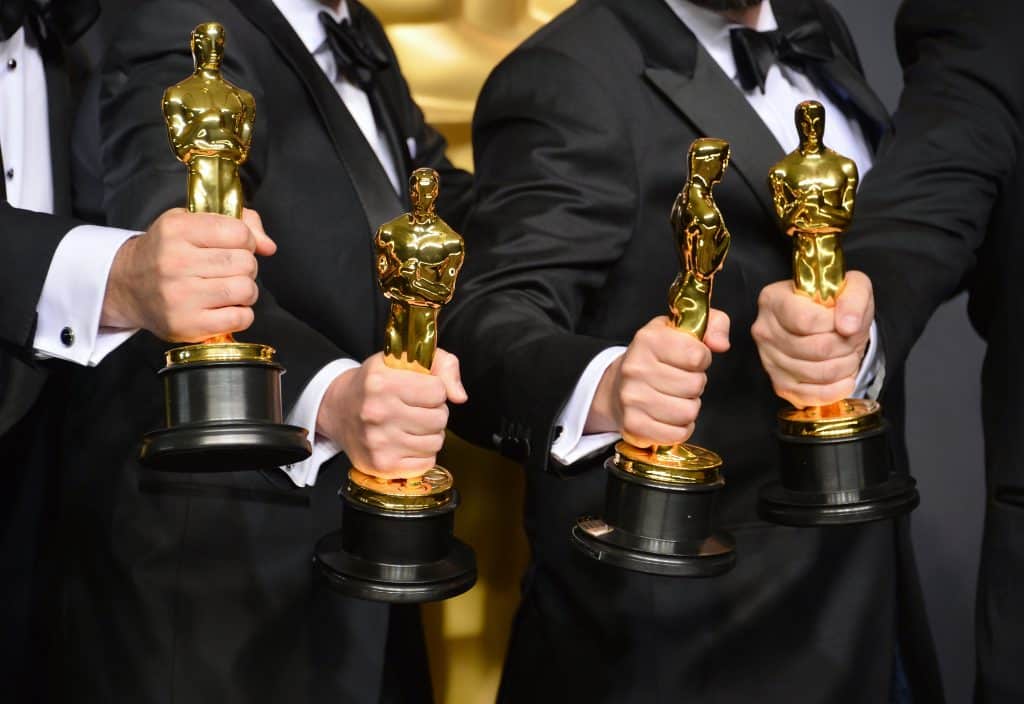 Four people hold Oscars