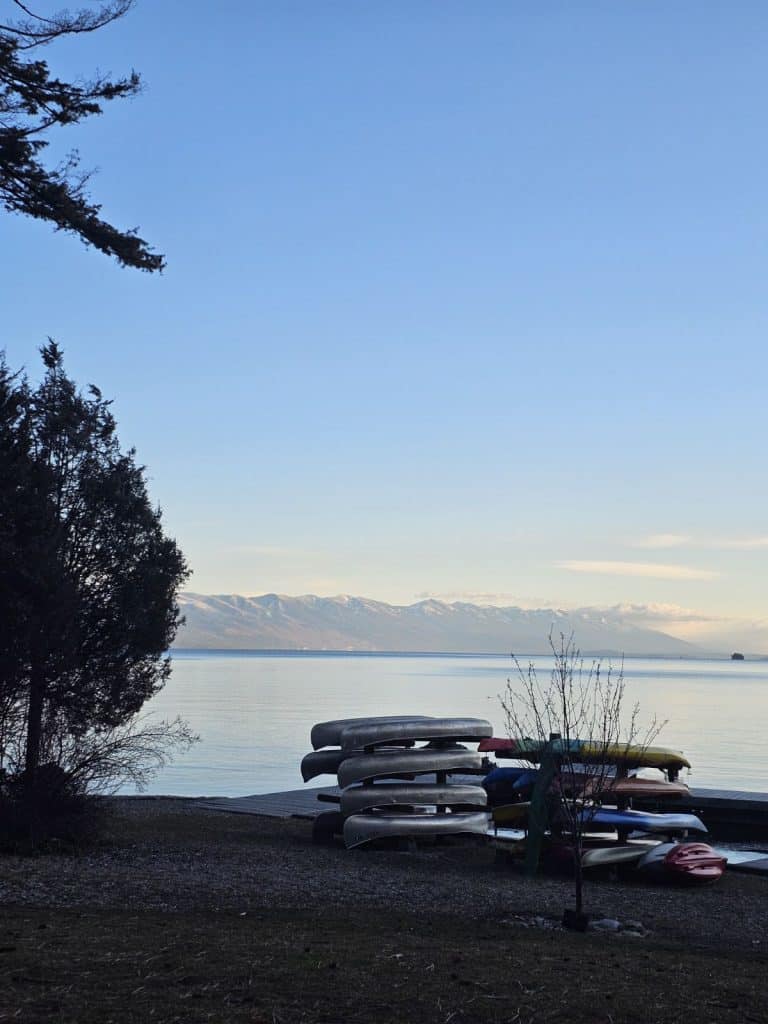 Canoes stacked on top of one another just before Flathead Lake, Montana. Blue skies just above the mountainous background.