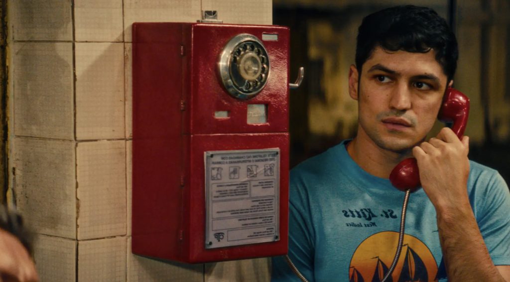 Bobbi (Gabriel Leone) on the telephone while scanning his surroundings apprehensively.