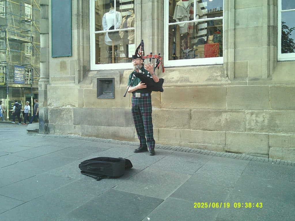 A bagpipe player performing on the sidewalk of Edinburgh, Scotland.