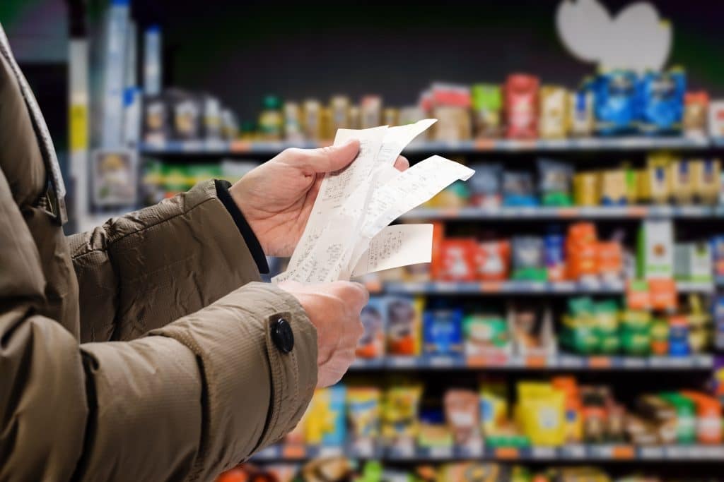 A man holding multiple grocery receipts.