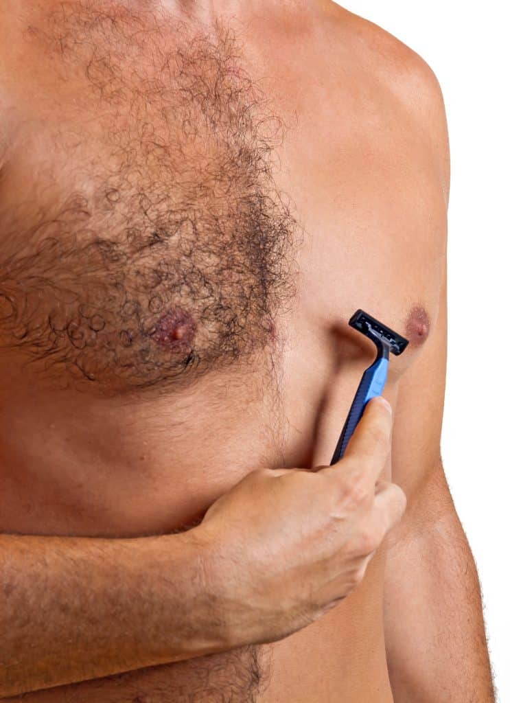 Image of a man's half-shaved chest, pictured beside his razer.