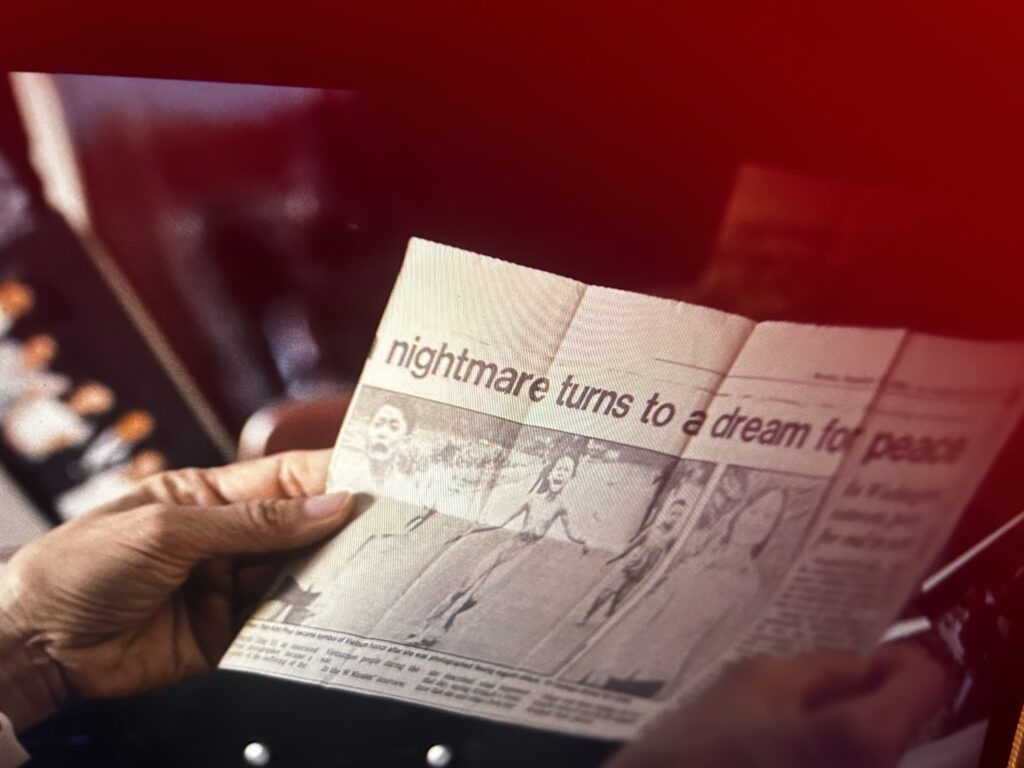 A woman holding a newspaper article of the "Napalm girl" photo.