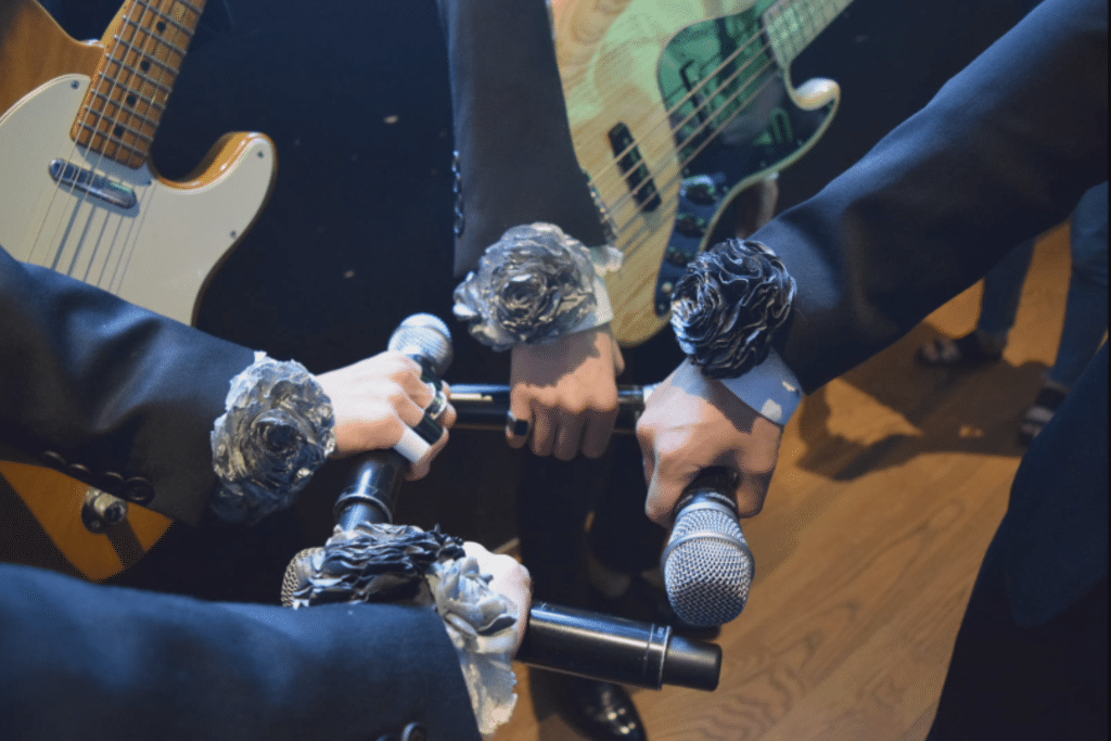 The Rose pre-show ritual with silver roses fist bumping their microphones before their concert.