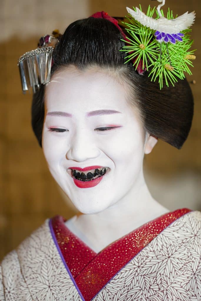 Image of an Asian woman done up as a Japanese Geisha, complete with the lead-white shin colour and the teeth painted black.