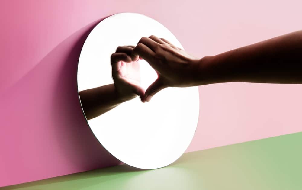 The reflection of a hand makes a heart in the mirror.