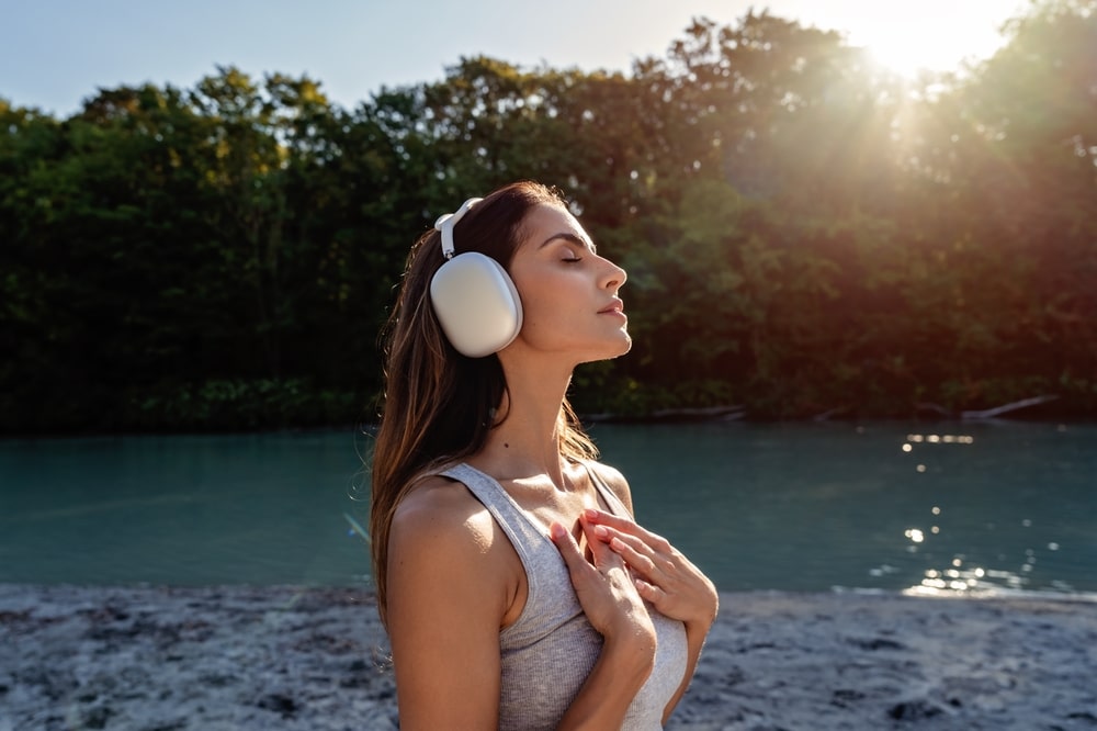 A woman in headphones savors the sun on the beach.