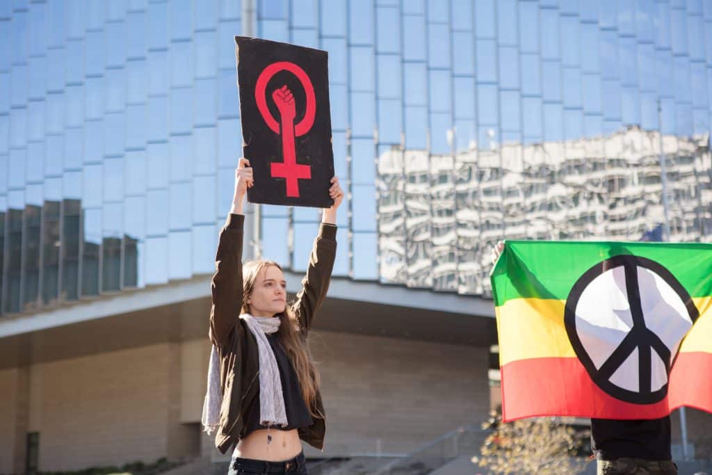 Woman holds up a sign with a feminist symbol.
